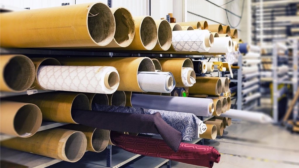 Sourcing sustainable fabrics and choosing the right production method Fashion designer reviewing fabric rolls and manufacturing options
